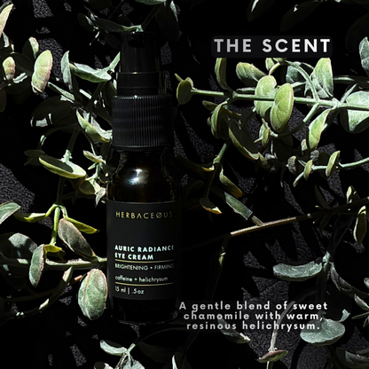 Herbaceous auric radiance eye cream bottle surrounded by green leaves on a dark background